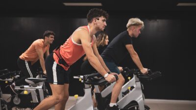 Indoor cycling studio with riders tracking real‑time performance metrics on wearables.