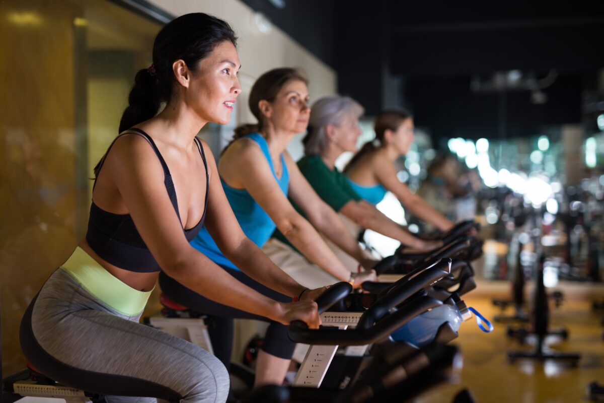 Indoor cycling studio with riders tracking real‑time performance metrics on wearables.