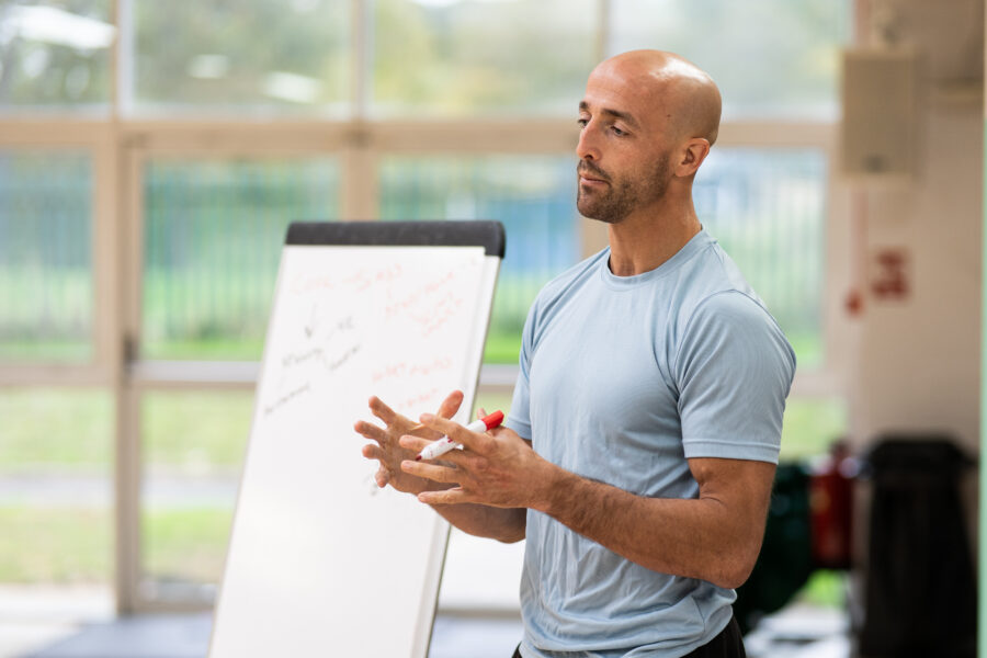 Man stood up looking like he's talking to a class