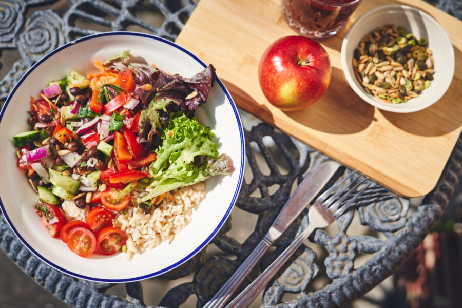 vibrant salad bowl with an apple and cup of seeds beside