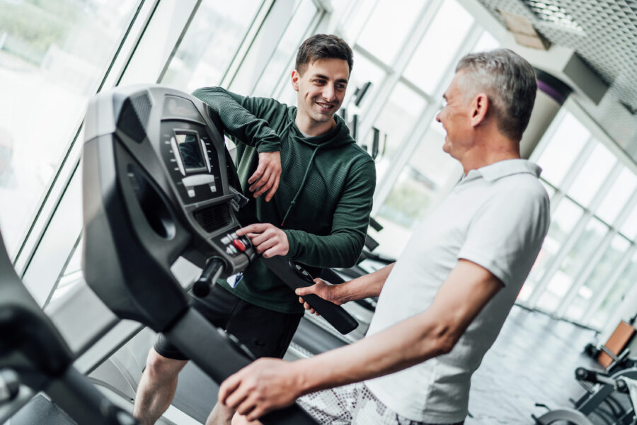 Personal trainer talking to a client whilst they are on a treadmill