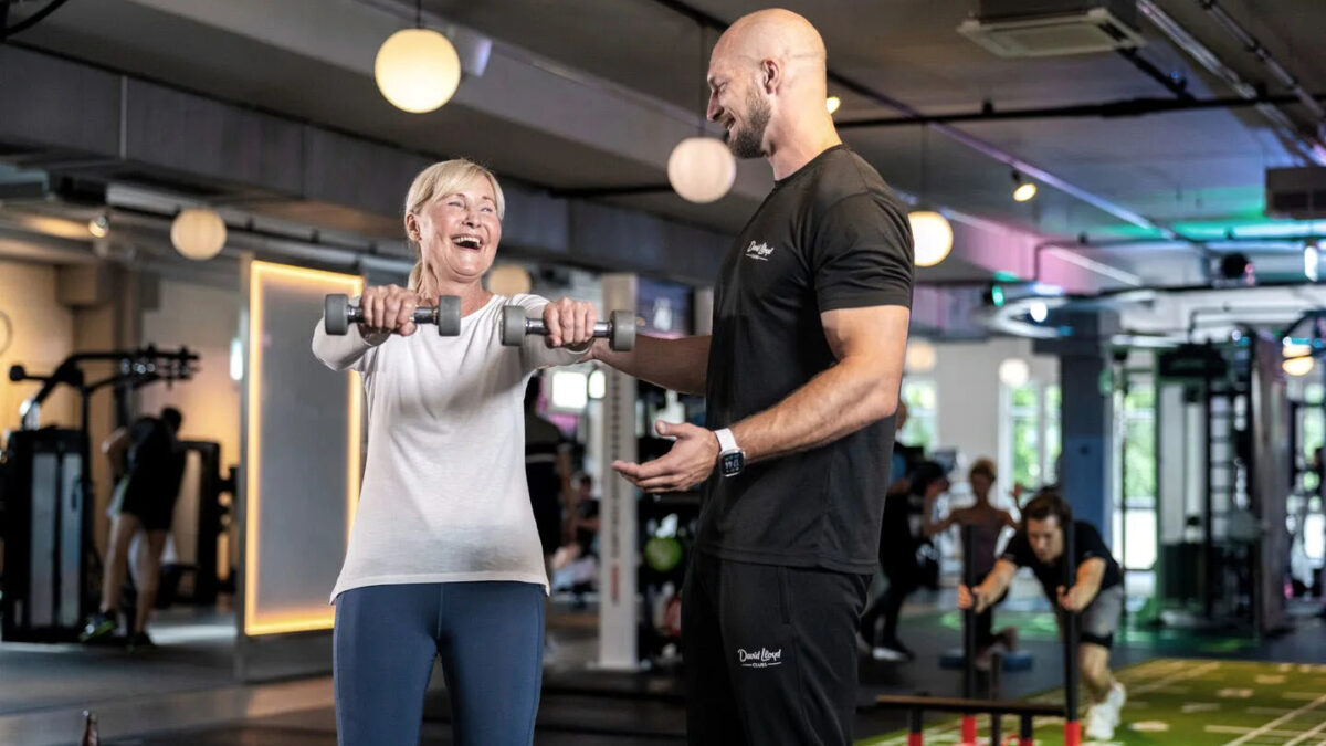 PT helping female perform dumbbell front raises